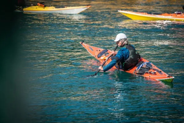 Seekajakfahrer schräg von hinten, auf der Kante rückwärts fahrend.